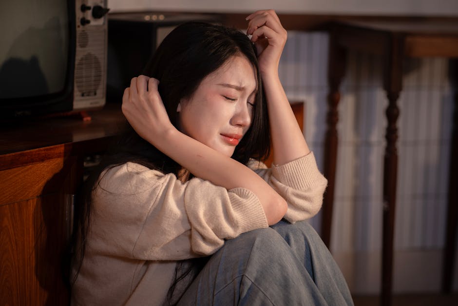 屋内に座り、深い精神的苦痛を表現している若い女性。