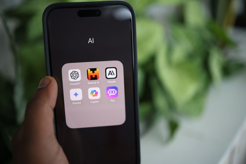 画面にAIアプリケーションが表示されたスマートフォンを持つ手のクローズアップ。