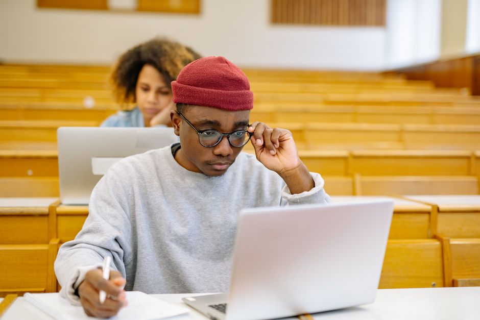 大学の講義室でノートパソコンを使っている若い成人たちが、課題に集中している。