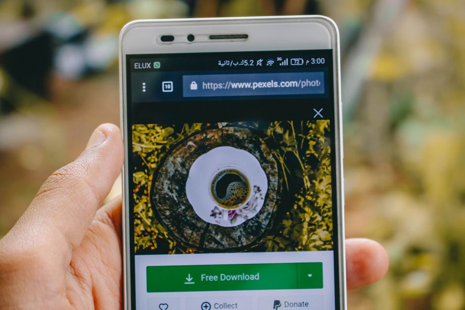 屋外でコーヒーカップの画像が表示されているスマートフォンのクローズアップ。