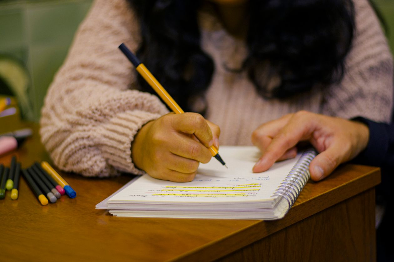 宅建参考書で勉強しながらカラーペンでノートにまとめる様子
