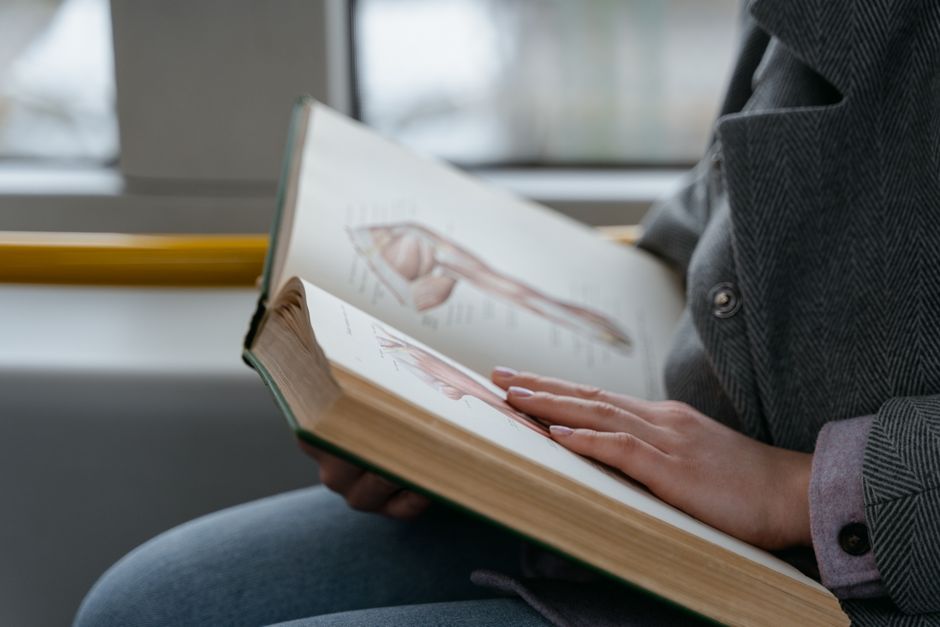 看護師資格を働きながら取る方法 通勤中に解剖学の参考書で学ぶ社会人のイメージ